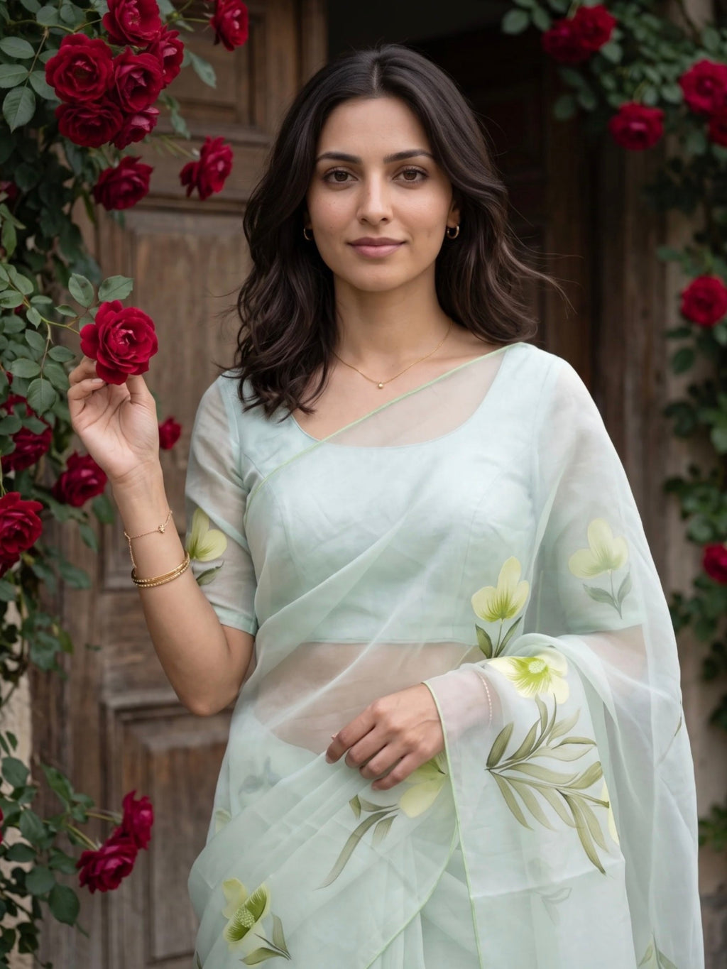 Woman wearing a light green saree with yellow floral prints and tassel detailing outdoors.