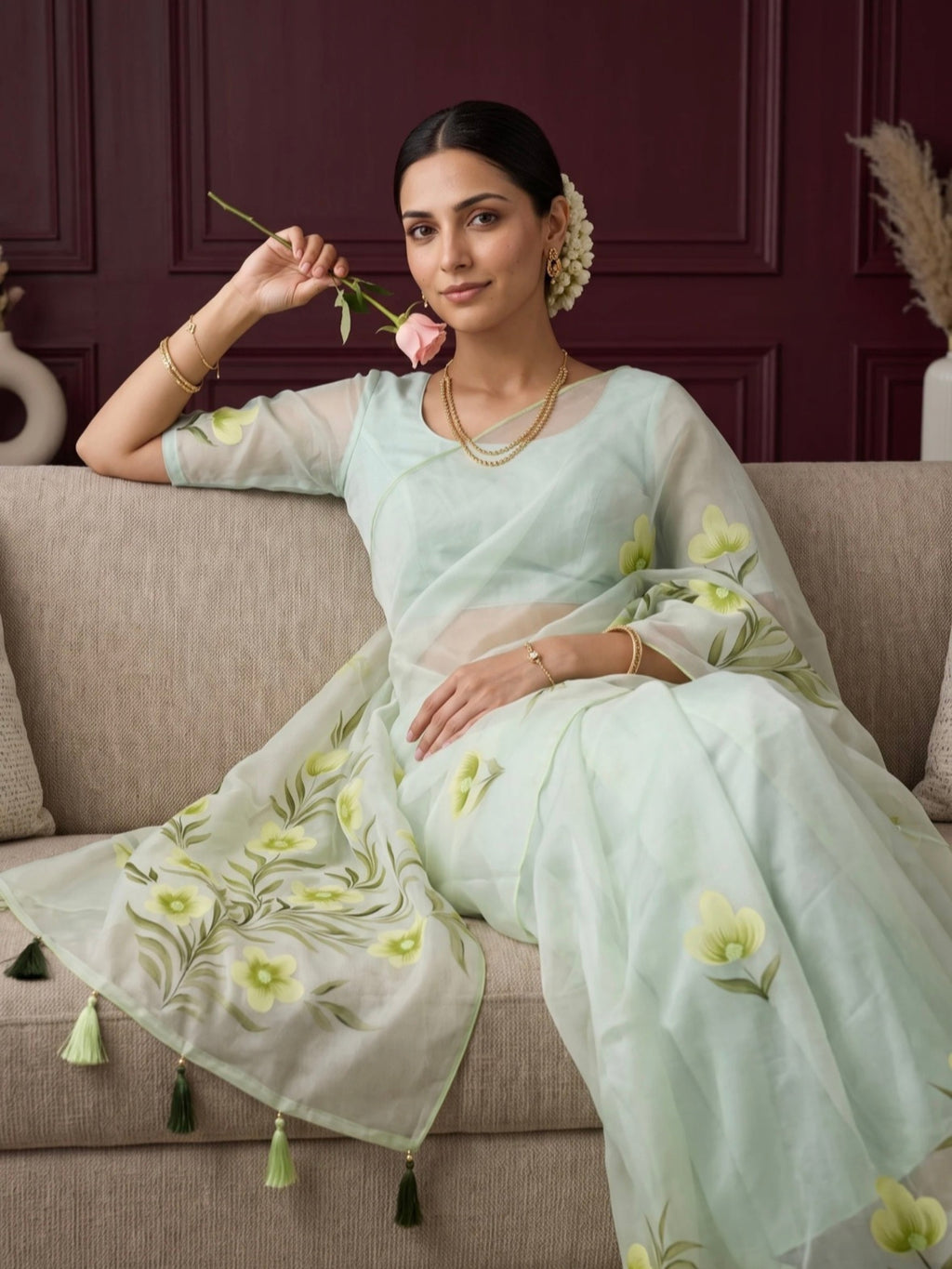 Woman wearing a light green saree with yellow floral prints and tassel detailing outdoors.