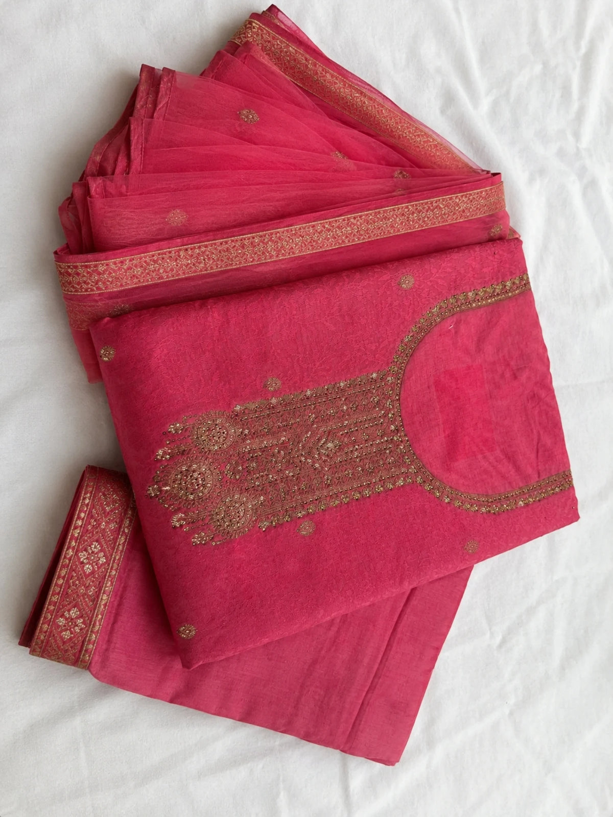 Woman wearing a pink embroidered suit with matching pants and a sheer dupatta indoors.