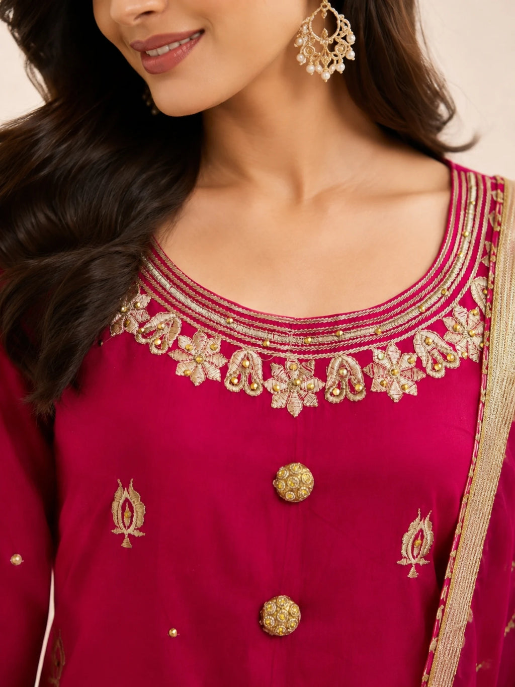 Woman wearing a pink embroidered suit with matching pants and a sheer dupatta indoors.