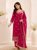 Woman wearing a pink embroidered suit with matching pants and a sheer dupatta indoors.