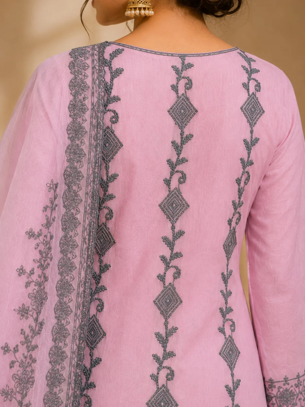 Woman wearing a pink suit with grey floral embroidery, matching pants and a flowing dupatta.