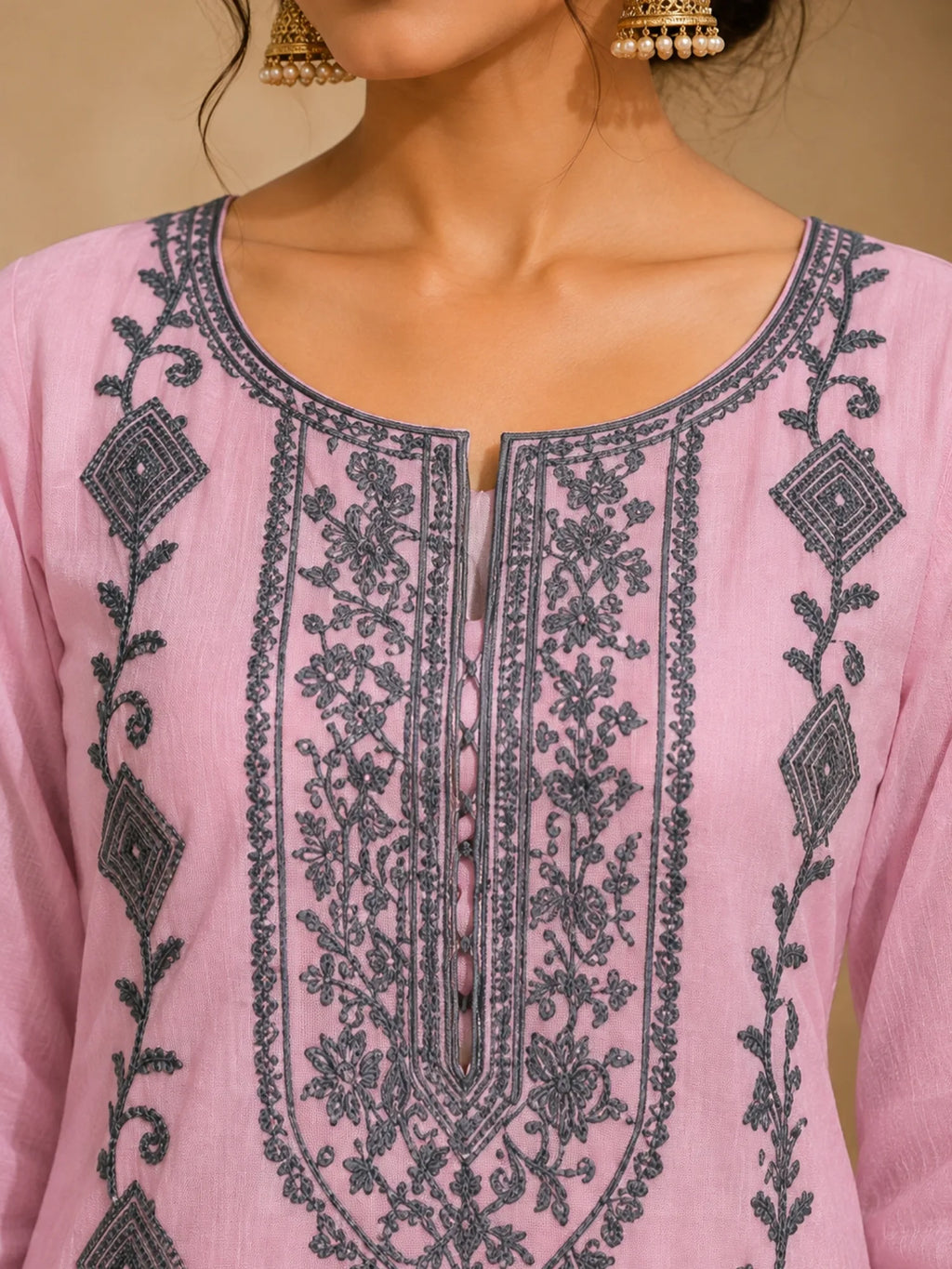 Woman wearing a pink suit with grey floral embroidery, matching pants and a flowing dupatta.