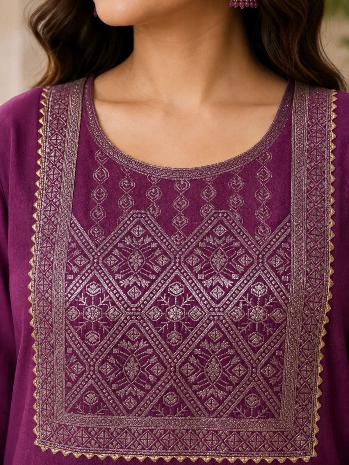Woman wearing a plum purple suit with embellished borders and a matching dupatta outdoors.