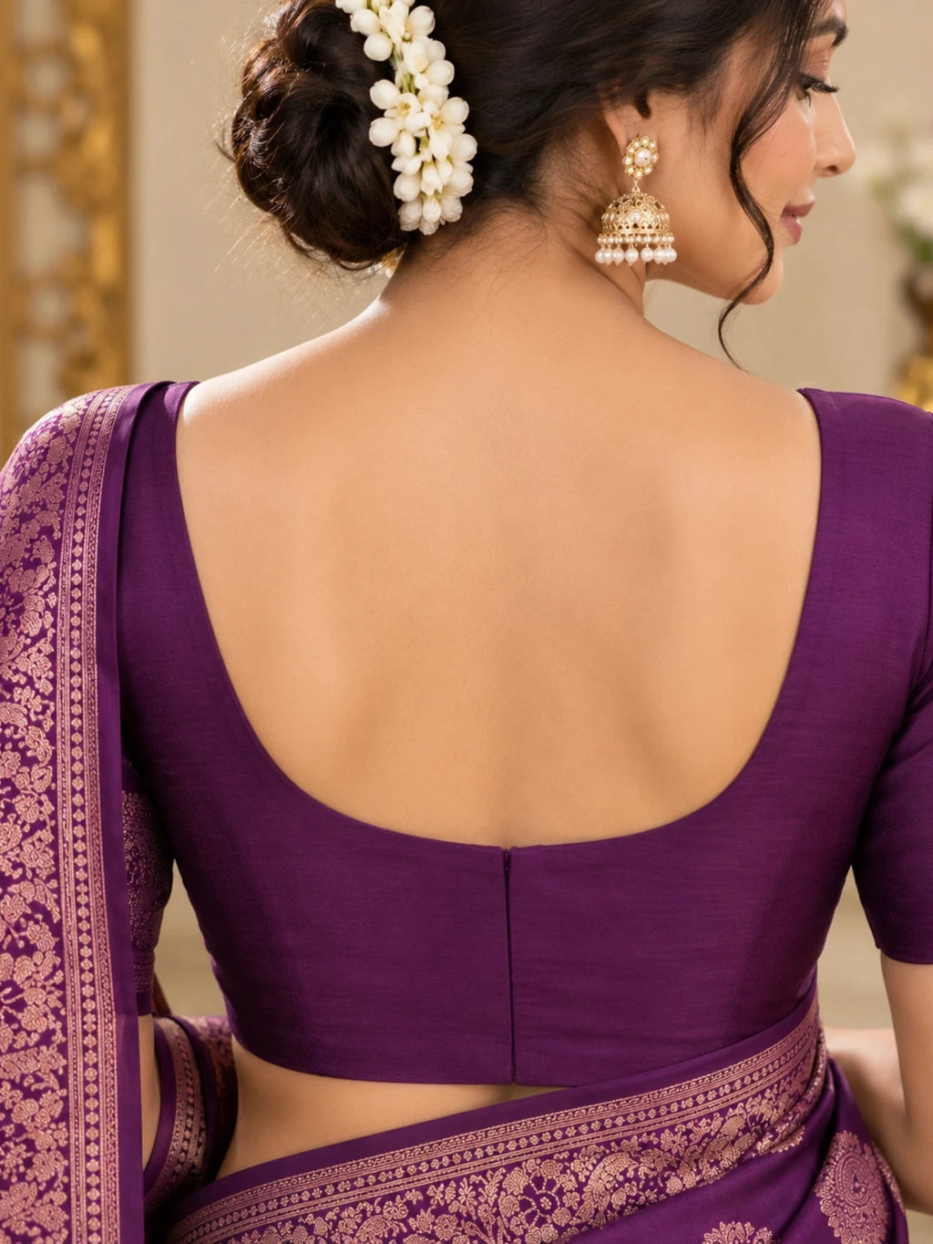 Purple silk saree with gold floral motifs and an ornate woven border on a woman.