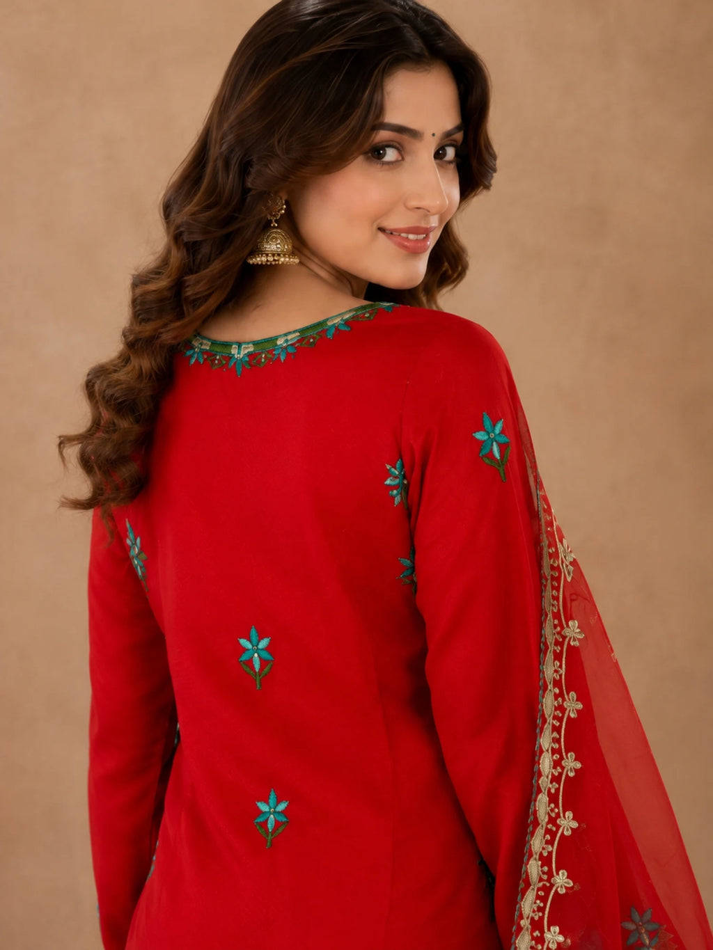 Red embroidered salwar suit with teal floral motifs and a sheer red dupatta with ornate borders.
