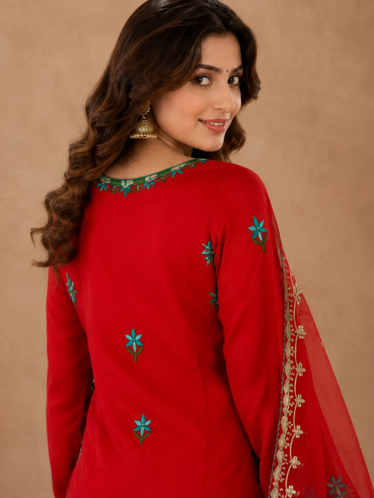 Red embroidered salwar suit with teal floral motifs and a sheer red dupatta with ornate borders.
