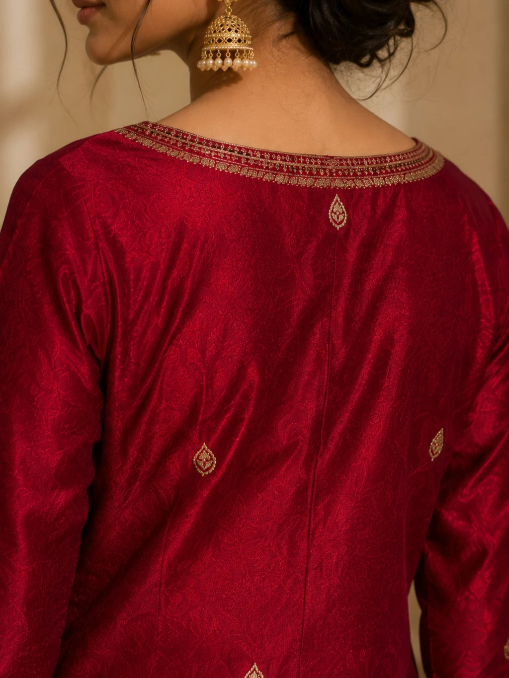 Woman wearing a deep red suit with gold embroidery, matching pants and an ornate dupatta.