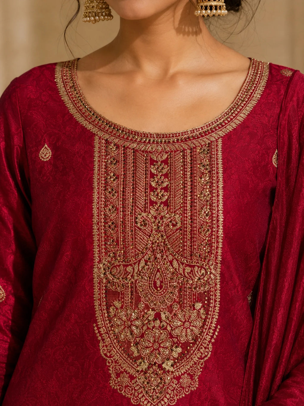Woman wearing a deep red suit with gold embroidery, matching pants and an ornate dupatta.