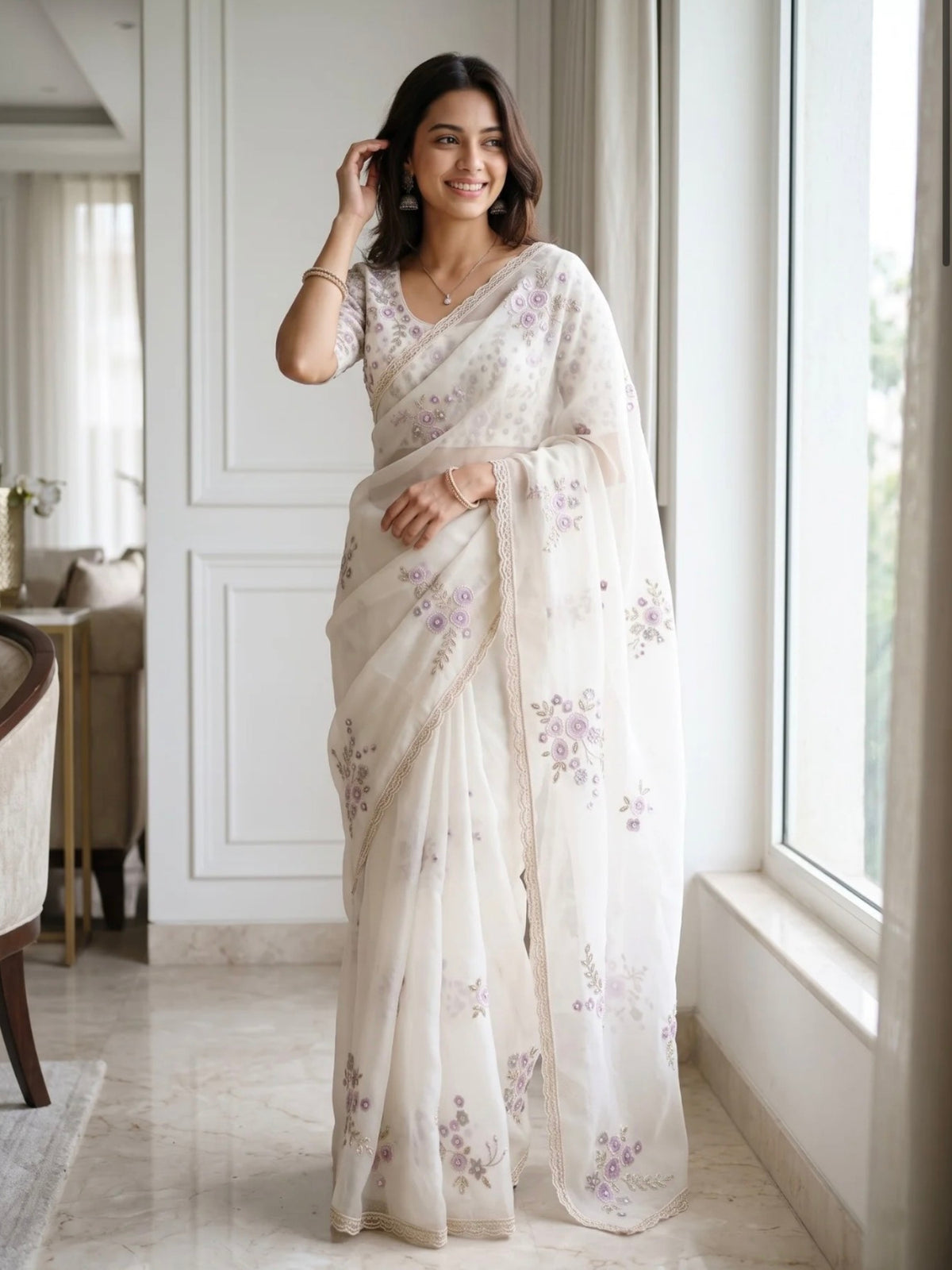 Woman wearing a white saree with lavender floral prints, standing on an elegant staircase.